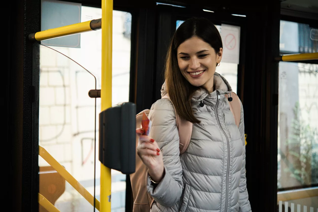 Une femme passe une carte bleue devant un valideur dans un bus